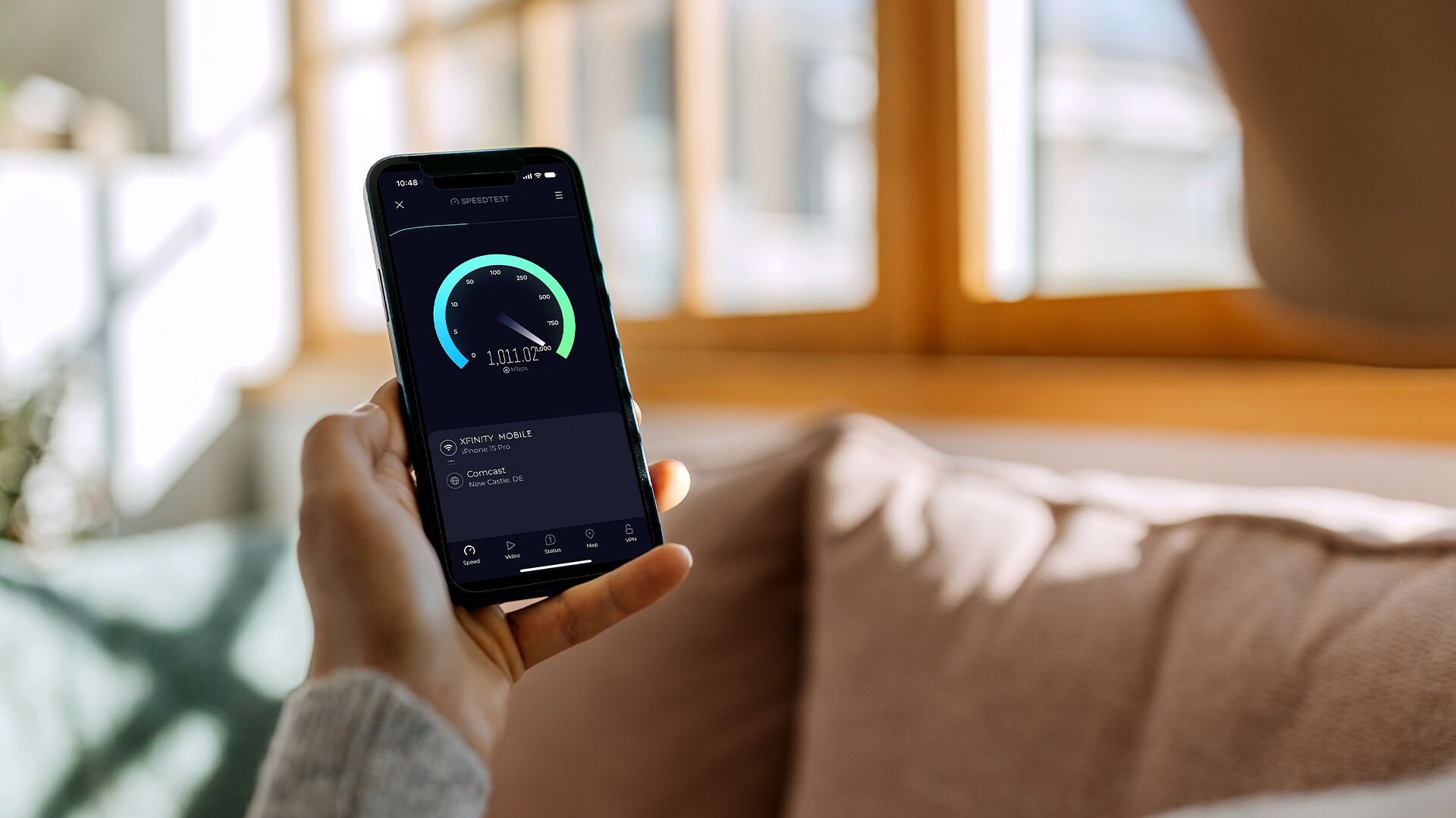 A person holding a phone that is displaying an Ookla internet speed test
