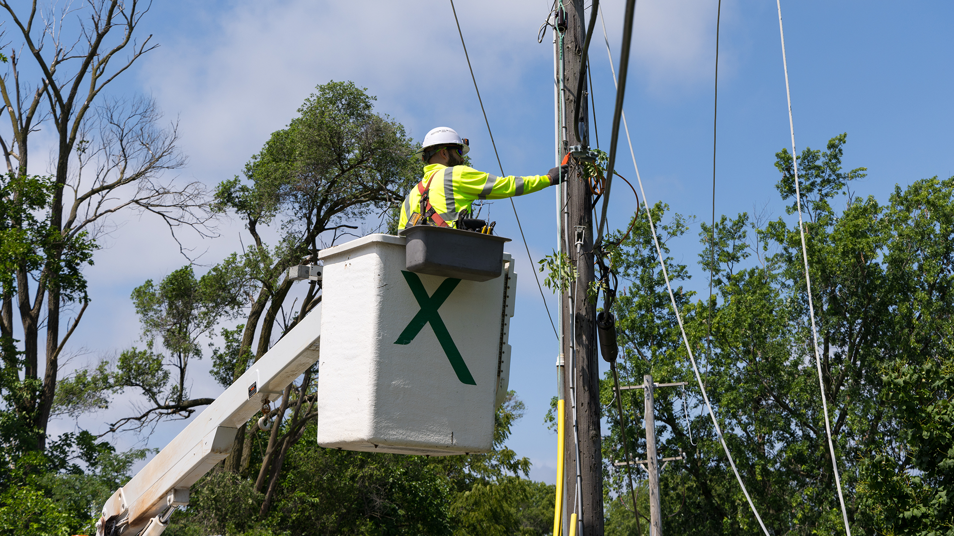 An Xfinity lineman repairing a cable on a telephone pole