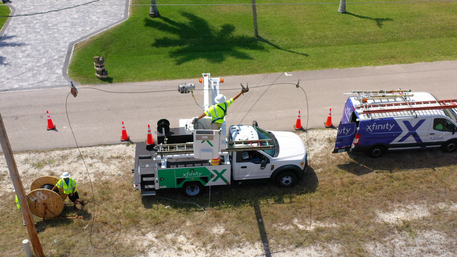 Xfinity technicians repairing a cable from a cherry picker