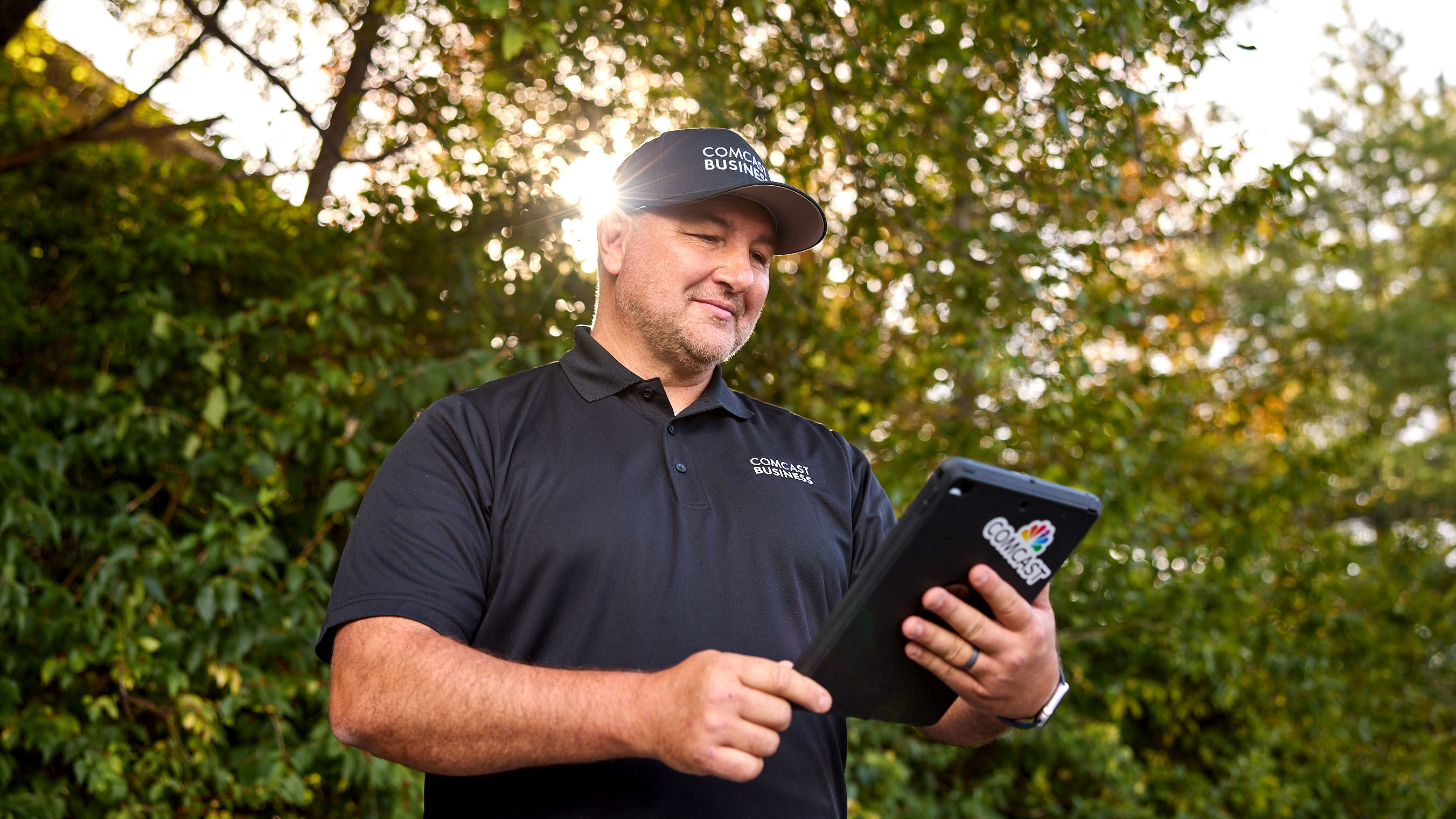 A Comcast Business technician looking at a tablet held in his hands
