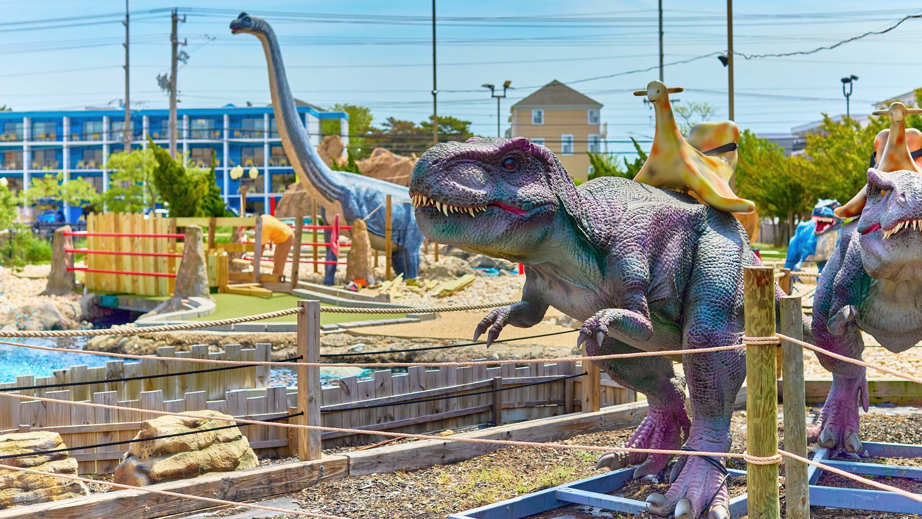 A minigolf course full of life-size dinosaur statues.
