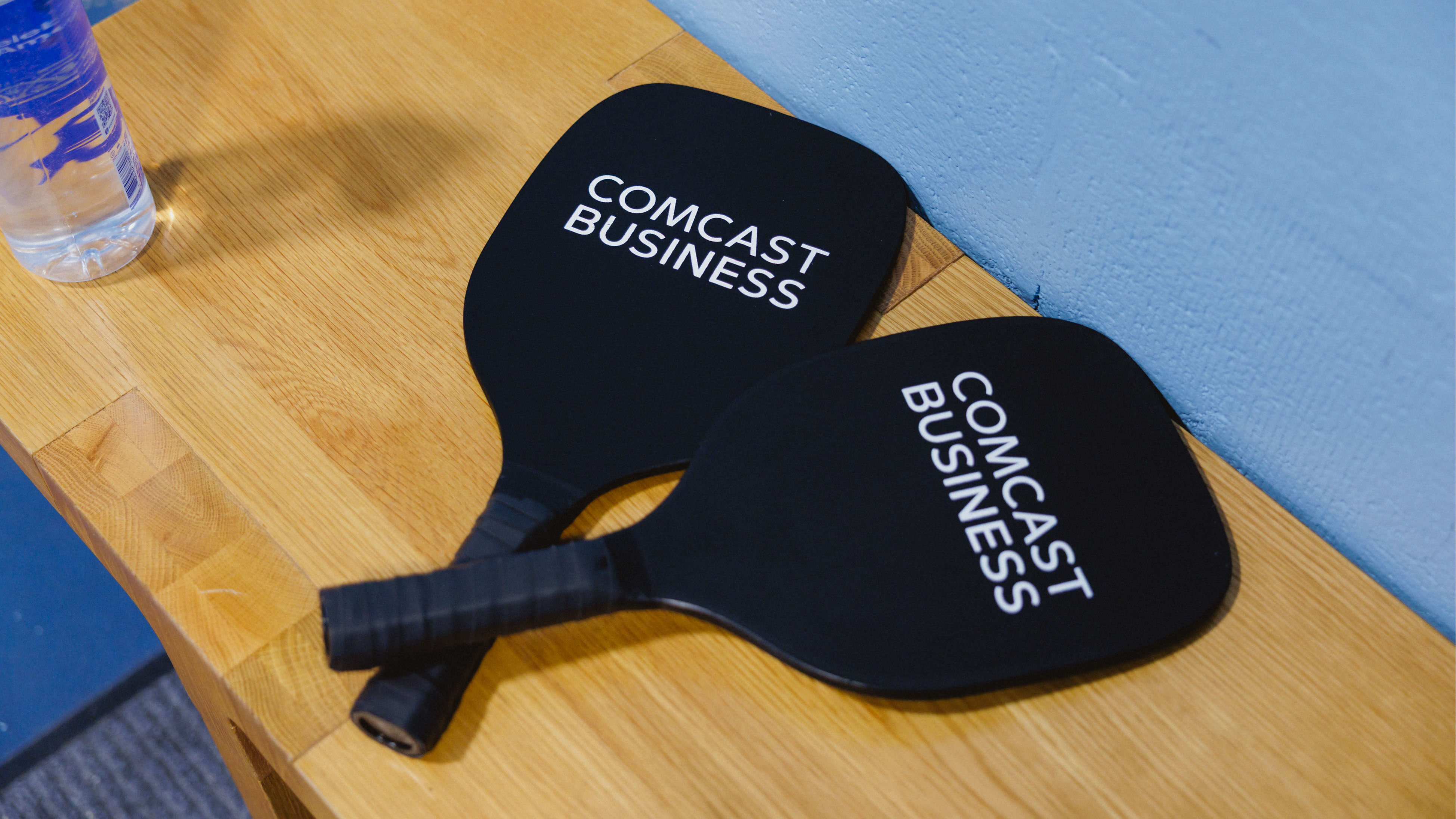 Two Comcast Business-branded pickleball paddles.