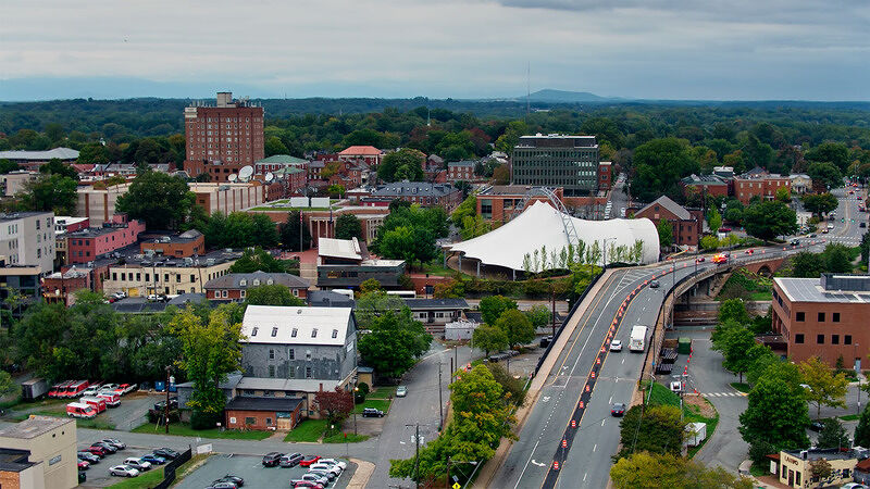 Aerial view of a town with roads, buildings, and tree-lined streets leading toward a highway