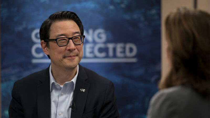 Youngmoo Kim smiling during an interview with a blue backdrop