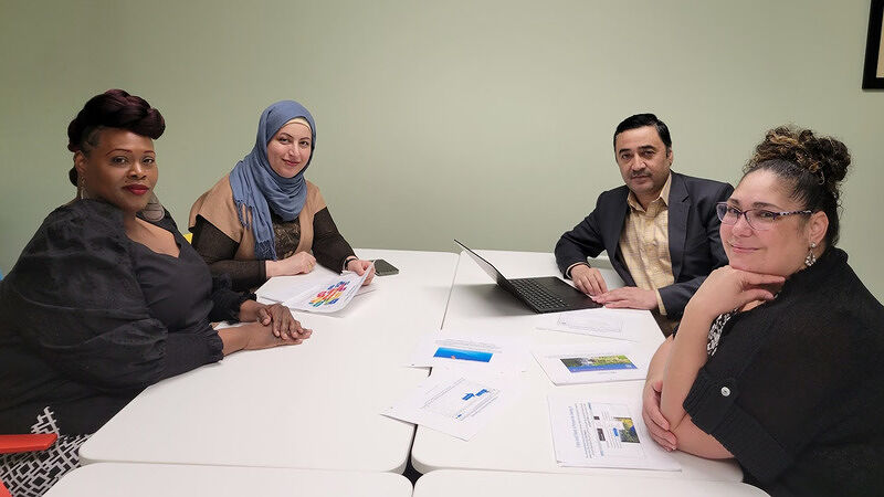 Four people seated around a conference table engaged in a workshop or meeting with papers and a laptop